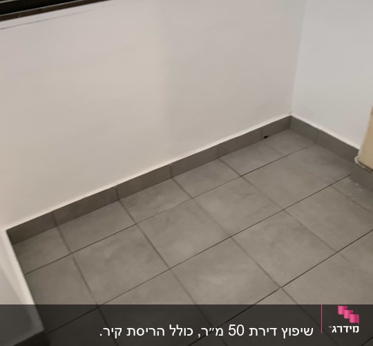 רצפה מרוצפת באריחים אפורים ליד קיר לבן
